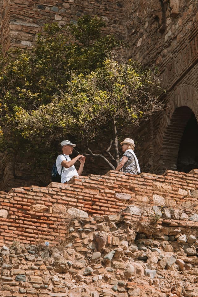 a retired couple taking pictures by a rock wall