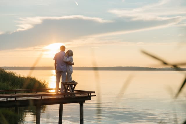 a retired couple hugging on a dock at sunset
